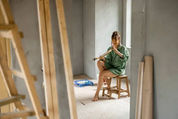 여자는 새로운 아파트의 수리를하는 페인트 의자에 앉아서 페인트 색상을 개념의 로열티 프리 스톡 사진