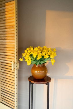 Güzel bir buket sarı lale vazoda, gün ışığında evdeki masada.