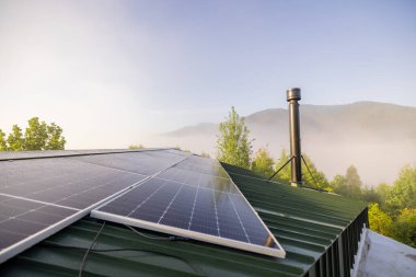 Yeşil çatıdaki güneş panelleri güneş enerjisini bir sis örtüsü gibi çevreleyen orman dağlarını kaplayarak sürdürülebilir teknolojiyi doğal güzellikle harmanlıyor.