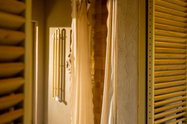 A sunlit shower space featuring soft beige tiles and a natural fabric curtain, creating a warm, cozy feel. Towel hooks and textured walls add a touch of rustic comfort clipart