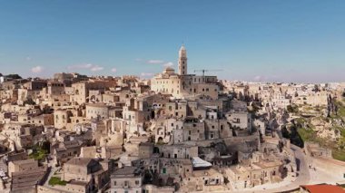 Matera, İtalya 'nın göz kamaştırıcı hava aracı görüntüsü, gün ışığında yıkandı. Eski taş şehir, ikonik Sassi mağarası evleri ve katedral çan kulesi