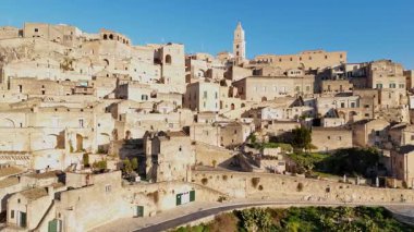 Matera Katedrali 'nin hava aracı görüntüsü antik şehir manzarasının üzerinde yükseliyor. Tarihi kasabanın merkezinde geleneksel taş konutlar ve ortaçağ mimarisi sergileniyor.