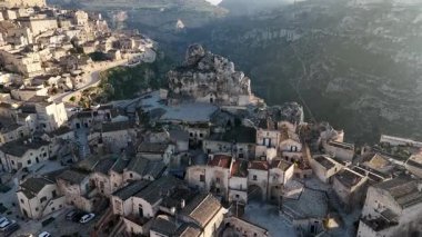 Basilica Cattedrale di Matera 'nın ve Matera, İtalya' daki antik taş konutların hava aracı görüntüsü. Engebeli tepelere oyulmuş tarihi manzara ortaçağ şehirlerini vurguluyor.