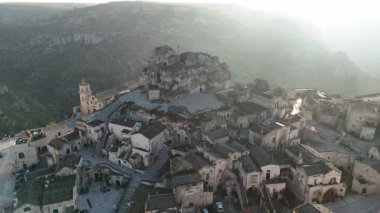 Basilica Cattedrale di Matera 'nın ve Matera, İtalya' daki antik taş konutların hava aracı görüntüsü. Engebeli tepelere oyulmuş tarihi manzara ortaçağ şehirlerini vurguluyor.