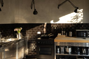 Siyah metro fayansları, paslanmaz çelik dolapları ve ahşap tezgahları olan şık endüstriyel mutfak.