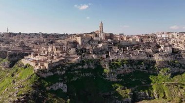 Matera, İtalya 'nın göz kamaştırıcı hava aracı görüntüsü, gün ışığında yıkandı. Sassi mağarası konutları ve katedral çan kulesiyle antik taş şehir olağanüstü bir UNESCO dünyası olarak duruyor.