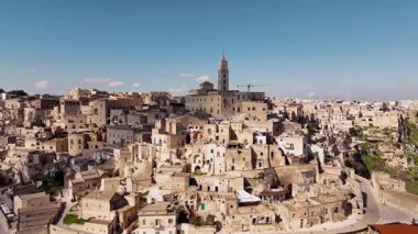 Matera, İtalya 'nın göz kamaştırıcı hava aracı görüntüsü, gün ışığında yıkandı. Eski taş şehir, ikonik Sassi mağarası evleri ve katedral çan kulesi