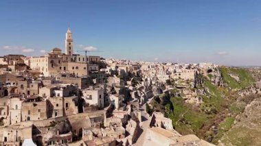 Matera, İtalya 'nın göz kamaştırıcı hava aracı görüntüsü, gün ışığında yıkandı. Eski taş şehir, ikonik Sassi mağarası evleri ve katedral çan kulesi