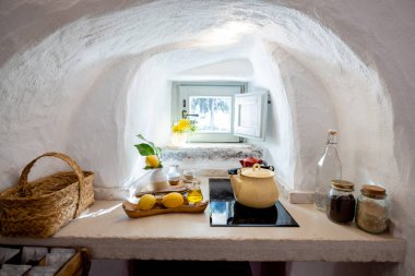 Kemerli pencereli kırsal trullo mutfağı, limonlar, zeytinyağı, el yapımı seramik ve sakin bir su ısıtıcısı yavaş yaşam cazibesiyle aşılanmış Akdeniz yemek köşesi.
