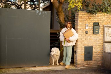 Bir kadın, büyük beyaz köpeğiyle bir paket taşıyarak Roma 'daki evinden dışarı çıkar. İtalya 'da yaşayan yavaş, otantik bir şehre bir bakış..
