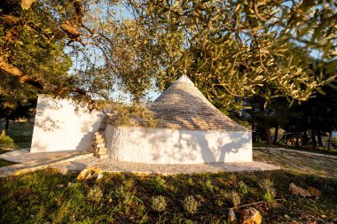 Konik taş çatılı geleneksel bir trullo Puglia kırsalında sessizce durur. Bu resim, seyahat tasarımı veya kültürel içerik için ideal kalıtım mimarisi ve kırsal basitliği yansıtır.
