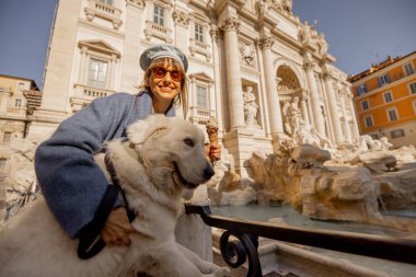 Gülümseyen kadın, Roma 'daki Trevi Çeşmesi' nin önünde dondurmasıyla selfie çeker ve güneşli bir günde Roma 'nın tatlı bir anını yakalar.