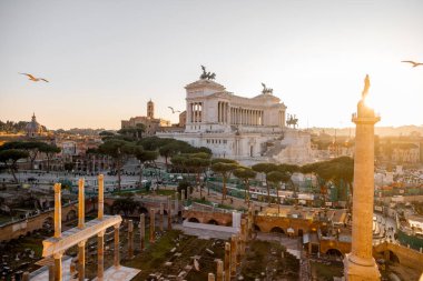 Capitoline Tepesi manzarası, Santi Luca e Martina Kilisesi, ve görkemli Altare della Patria Roma çamları ve kuşların çatılarda süzüldüğü altın ışıkla yıkandı.
