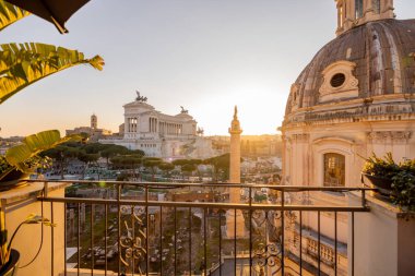 Gün batımı, Roma Forumu 'nun antik kalıntılarını ve Meryem Ana' nın Kutsal Kilisesi 'nin kubbesini silip süpürüyor. Uzakta Altare della Patria var.