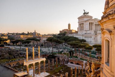 Capitoline Tepesi manzarası, Santi Luca e Martina Kilisesi, ve görkemli Altare della Patria Roma çamları ve kuşların çatılarda süzüldüğü altın ışıkla yıkandı.