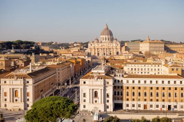 Castel Sant Angelo 'dan Vatikan Şehri ve St. Peters Bazilikası üzerinde geniş çaplı bir manzara, tarihi binalar ve Roma çam ağaçlarıyla çevrili Via della Conciliazione' nin planını ele geçiriyor.