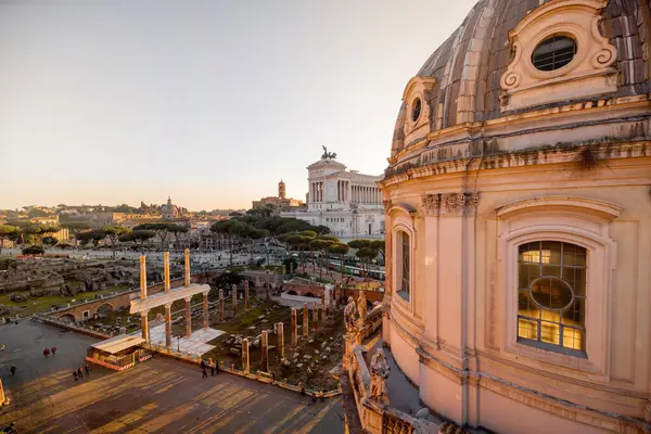 Gün batımı, Roma Forumu 'nun antik kalıntılarını ve Meryem Ana' nın Kutsal Kilisesi 'nin kubbesini silip süpürüyor. Uzakta Altare della Patria var.