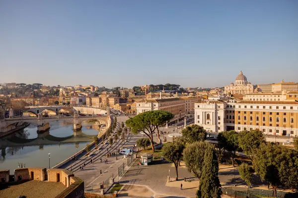 Castel Sant Angelo 'dan Vatikan Şehri ve St. Peters Bazilikası üzerinde geniş çaplı bir manzara, tarihi binalar ve Roma çam ağaçlarıyla çevrili Via della Conciliazione' nin planını ele geçiriyor.
