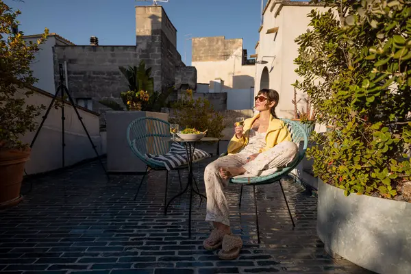Bir kadın güneşli bir çatıda şarap ve taze salatayla rahatlar. Resim yavaş yaşam, seyahat, konukseverlik ve sağlık yaşam tarzı içeriği için idealdir.