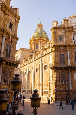 Palermo 'daki Quattro Canti Meydanı' nda altın ışığın barok cepheleri aydınlattığı yerde insanlar geziniyor. Bu fotoğraf, Sicilya 'daki kentsel keşiflerin mimari zarafetini ve cazibesini yansıtıyor.