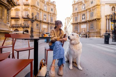 Bir kadın, Palermo 'da bir kafede geleneksel Sicilya dondurmasının tadını çıkarırken köpeğiyle güzel bir anı paylaşıyor. Görüntü sıcaklığı, dostluğu ve otantik yerel yaşam tarzını yakalıyor.
