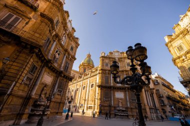 Palermo 'daki Quattro Canti Meydanı' nda altın ışığın barok cepheleri aydınlattığı yerde insanlar geziniyor. Bu fotoğraf, Sicilya 'daki kentsel keşiflerin mimari zarafetini ve cazibesini yansıtıyor.