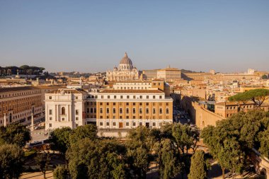 Vatikan Şehri 'nin panoramik manzarası ve Aziz Peters Bazilikası' nın tepesinden Roma çamları ve sabah güneşiyle Roma 'nın çatılarının üzerine kurulmuş Sant Angelo Kalesi.