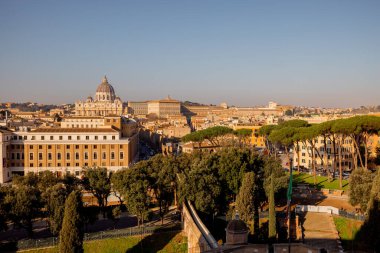 Vatikan Şehri 'nin panoramik manzarası ve Aziz Peters Bazilikası' nın tepesinden Roma çamları ve sabah güneşiyle Roma 'nın çatılarının üzerine kurulmuş Sant Angelo Kalesi.