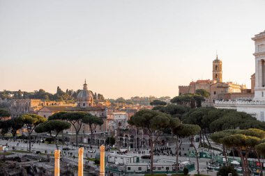 Capitoline Tepesi manzarası, Santi Luca e Martina Kilisesi, ve görkemli Altare della Patria Roma çamları ve kuşların çatılarda süzüldüğü altın ışıkla yıkandı.