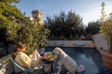 Güney İtalya 'da güneşli bir terasta büyük beyaz bir köpekle gevşemiş bir öğle yemeği. Akdeniz yaşam tarzını, hayvan dostu seyahatleri ya da açık hava yemek kavramlarını desteklemek için mükemmel.