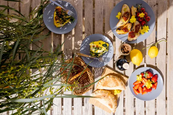 Taze meyve, limon, bruschetta ve zeytinyağlı ahşap bir masada canlı Akdeniz brunch 'ı. Doğal ışık ve rahat açık hava atmosferiyle kırsal yaz manzarası