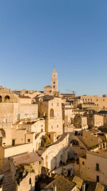 Matera, İtalya 'nın havadan görünüşü, altın sabah ışığıyla yıkanmış. Kanyon üzerinde yükselen ikonik taş evler ve katedral kulesi UNESCO tarafından listelenmiş bu tarihi harikayı gözler önüne seriyor.