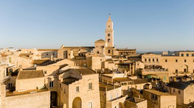 Matera, İtalya 'nın havadan görünüşü, altın sabah ışığıyla yıkanmış. Kanyon üzerinde yükselen ikonik taş evler ve katedral kulesi UNESCO tarafından listelenmiş bu tarihi harikayı gözler önüne seriyor.