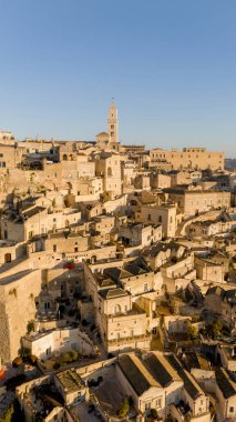 Matera, İtalya 'nın havadan görünüşü, altın sabah ışığıyla yıkanmış. Kanyon üzerinde yükselen ikonik taş evler ve katedral kulesi UNESCO tarafından listelenmiş bu tarihi harikayı gözler önüne seriyor.