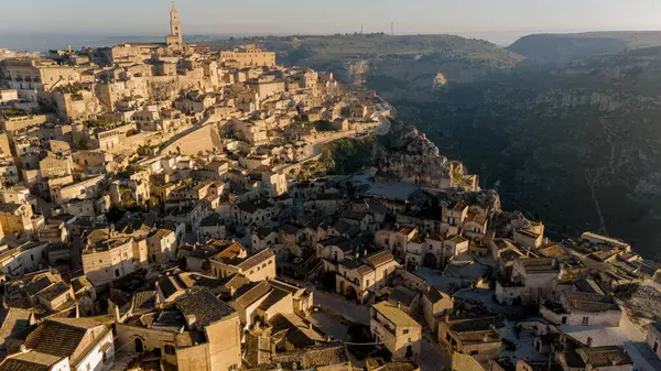 Matera, İtalya 'nın hava manzarası, altın gündoğumunda kanyonun üzerinde yükselen antik Sassi mağarası konutlarının ve katedrallerinin tam ölçeklerini gözler önüne seriyor. Zamansız ve dramatik bir UNESCO sitesi