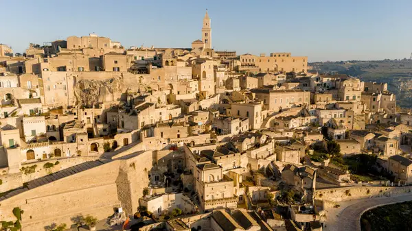 Matera, İtalya 'nın havadan görünüşü, altın sabah ışığıyla yıkanmış. Kanyon üzerinde yükselen ikonik taş evler ve katedral kulesi UNESCO tarafından listelenmiş bu tarihi harikayı gözler önüne seriyor.