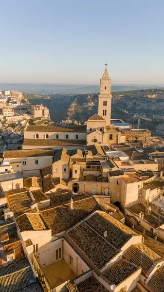 Matera, İtalya 'nın havadan görünüşü, altın sabah ışığıyla yıkanmış. Kanyon üzerinde yükselen ikonik taş evler ve katedral kulesi UNESCO tarafından listelenmiş bu tarihi harikayı gözler önüne seriyor.