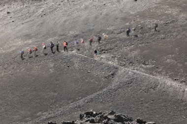 Etna volkanik kraterine doğru yürüyen yürüyüşçüler ve turistler