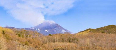 Cratere del vulcano Etna durante giornata di sole e cielo blu con emission di fumo