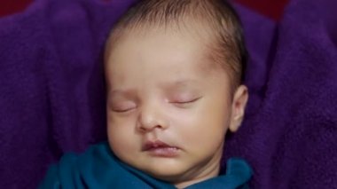 Bebek ultrason fotokopisini elinde tutuyor ve bebek ambalajında uyuyor.