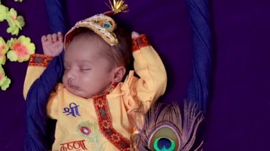 Krishna 'da yeni doğmuş bir erkek bebek. Farklı açılardan farklı bir şekilde sallanan aksesuarlarla süslenmiş.