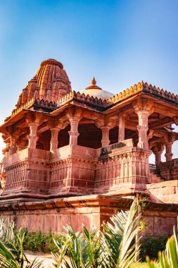 Mandore Garden Jodhur Rajasthan Hindistan 'da çekilen eşsiz açıyla parlak mavi gökyüzü ile antik Hindu tapınağı mimarisi.