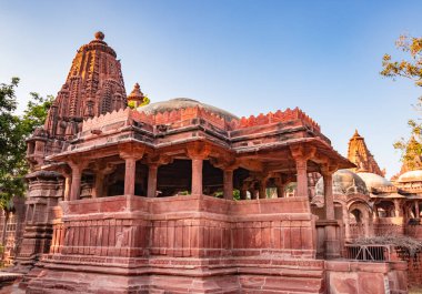 Mandore Garden Jodhpur Rajasthan Hindistan 'da çekilen eşsiz bir açı ile parlak mavi gökyüzü ile antik Hindu tapınağı mimarisi.