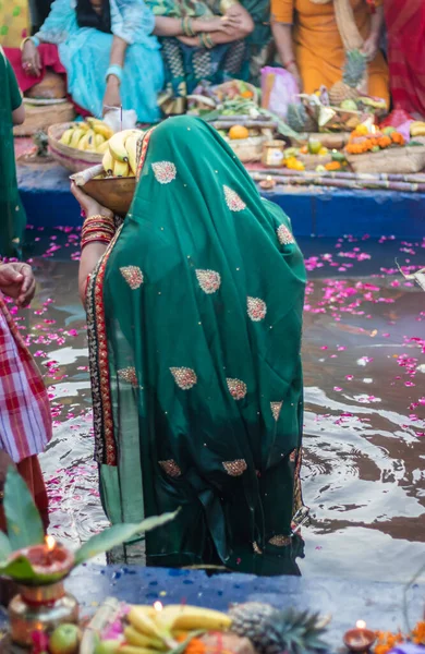 devotee praying with religious offerings for sun god in Chhath festival