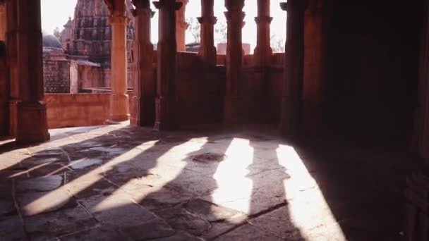 昼間独特の角度から赤い石の古代ヒンドゥ寺院建築をバックライト — ストック動画