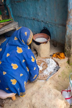 Kadınlar geleneksel toprak damarlarında pirinç zeminli ekmek yapıyorlar, tahta ateşinde farklı açılardan.