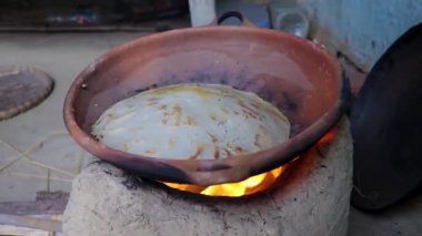 Geleneksel toprak kaplarında pirinç ekmeği yapan kadınlar köyün farklı açılarından odun ateşinde yanarlar.