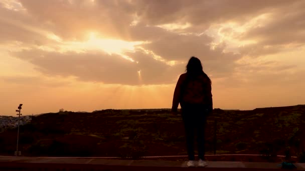 女孩背光拍摄与日落戏剧性的天空与太阳光与黄昏乌云 — 图库视频影像