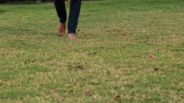 Genç adam akşam bahçedeki yeşil çimlerde yürüyor.