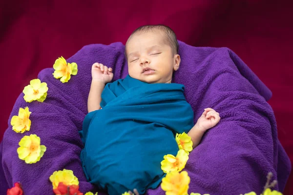 可爱的新生婴儿睡觉时 用独特风格的花朵包裹着婴儿 从顶角拍摄 图库照片